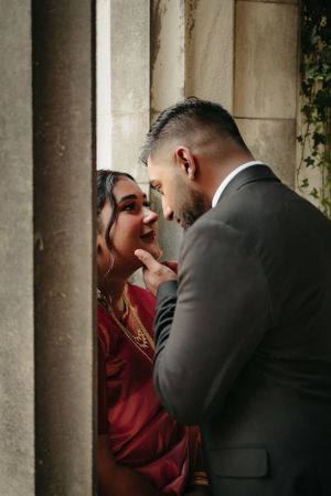 Intimate closeup of couple against stone column in dramatic lighting.