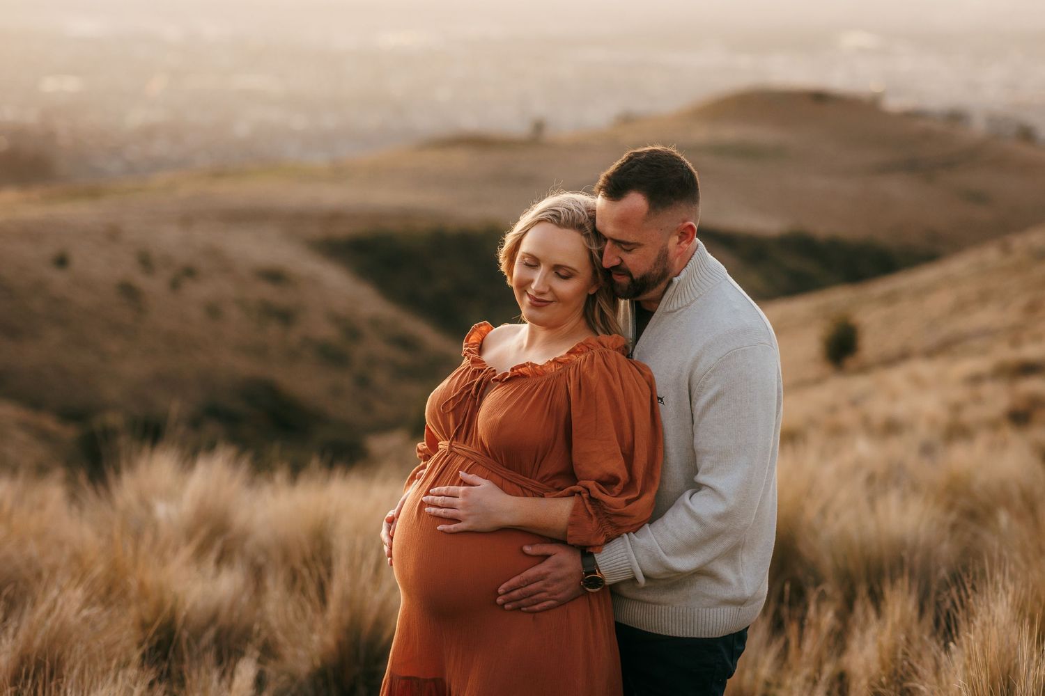 couple holding lovingly holding their baby wrapped in russet brown tones