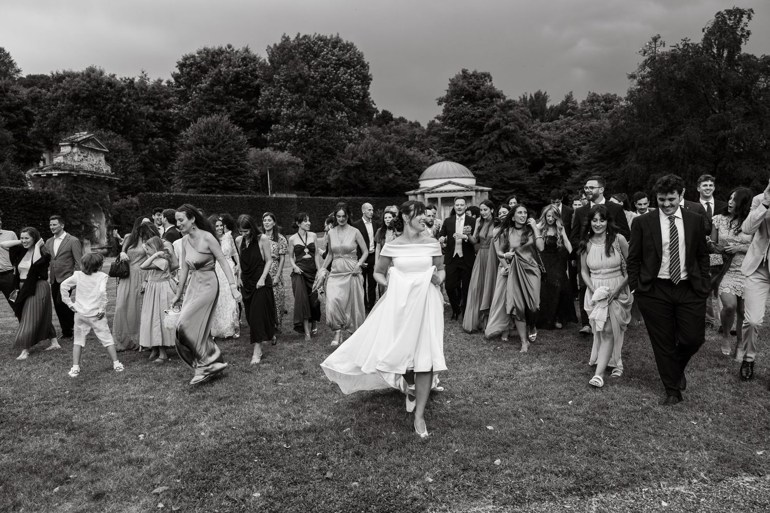 A blurred motion wedding photo of a couple walking together outside a gothic cathedral in formal attire.