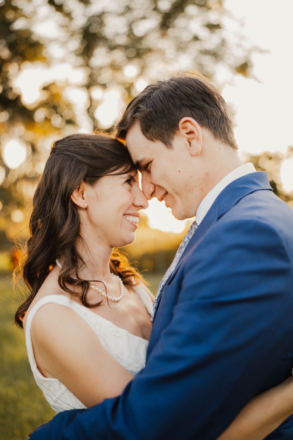 Romantic couple in wedding attire sharing intimate moment during golden hour.