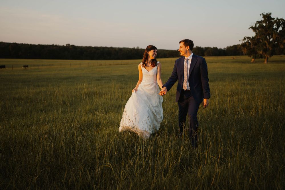 A romantic sunset photoshoot of newlyweds walking and dancing in a golden field.