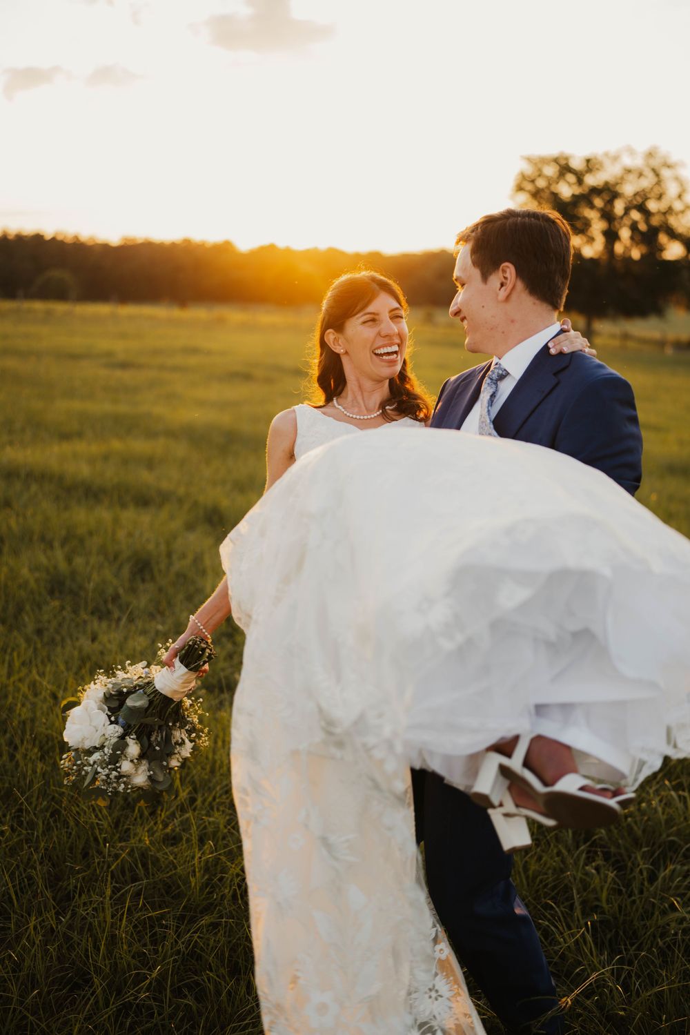 Couple playfully twirling and dancing together in a sunlit meadow at golden hour.