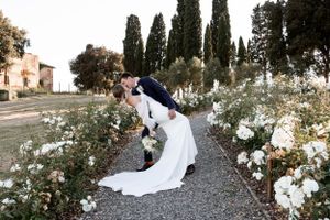 Wedding photographer in Tuscany, Italy. Couple do a dip kiss amongst beautiful flowers. May wedding in Tuscany.