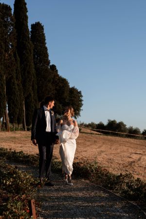 Couple walking down to their outside dinner area in wedding in Tuscany, Italy during golden hour.