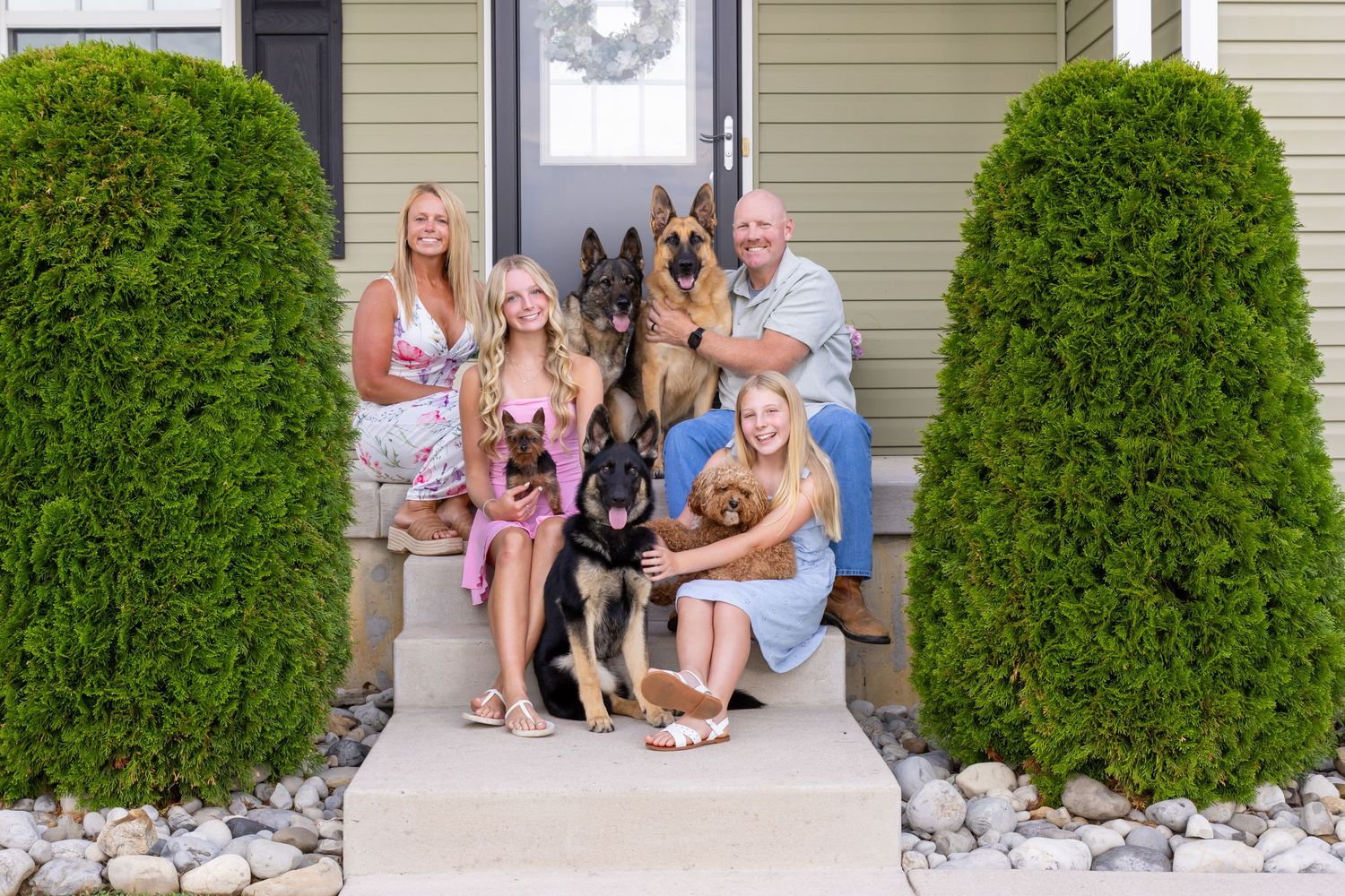 Family of four with two German Shepherds and a small dog posing on front porch steps of a home. Salem and Gloucester County Family Portraits