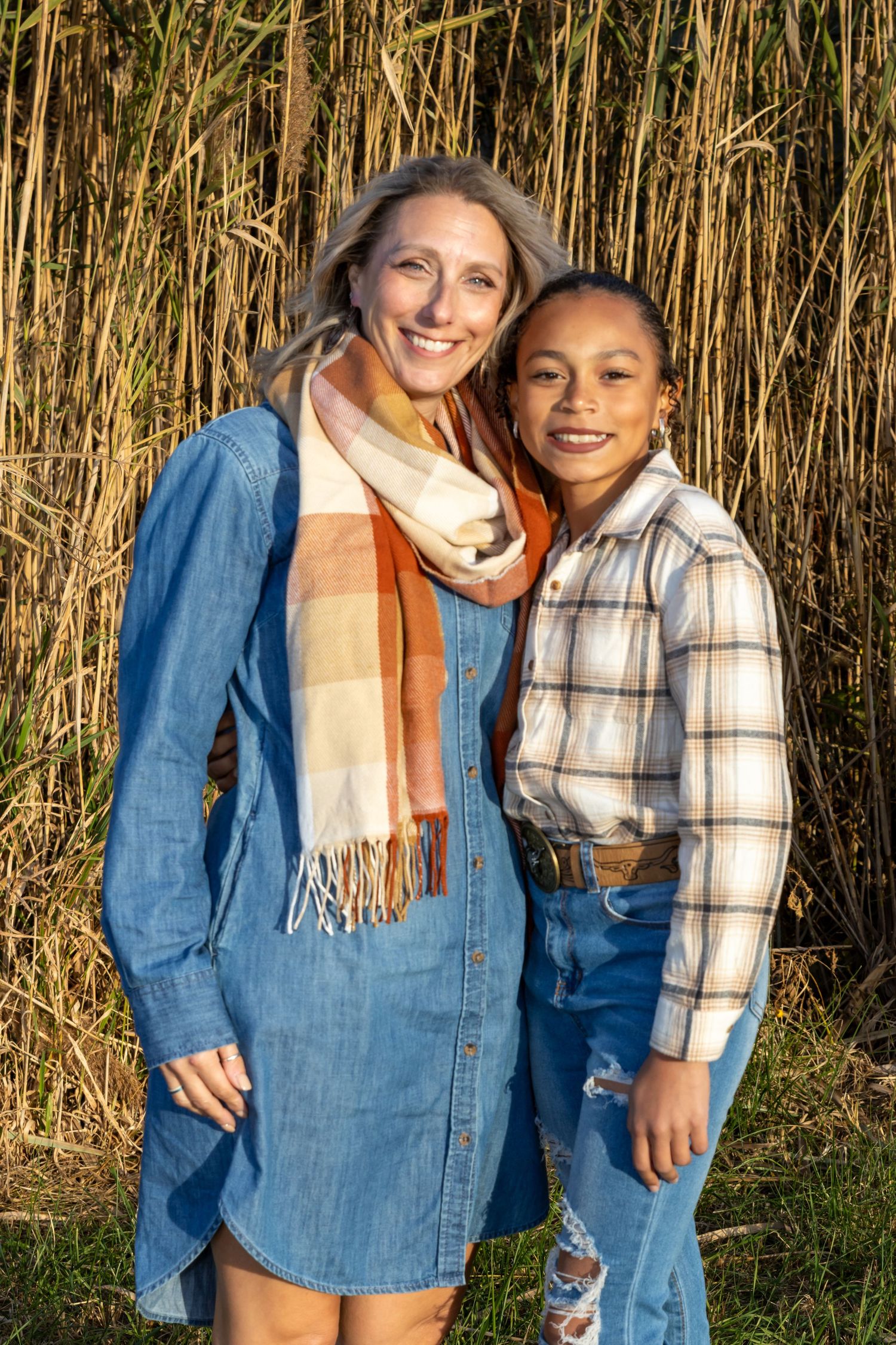 portrait of a mother and daughter that share a warm moment together against a backdrop of tall golden grass.
