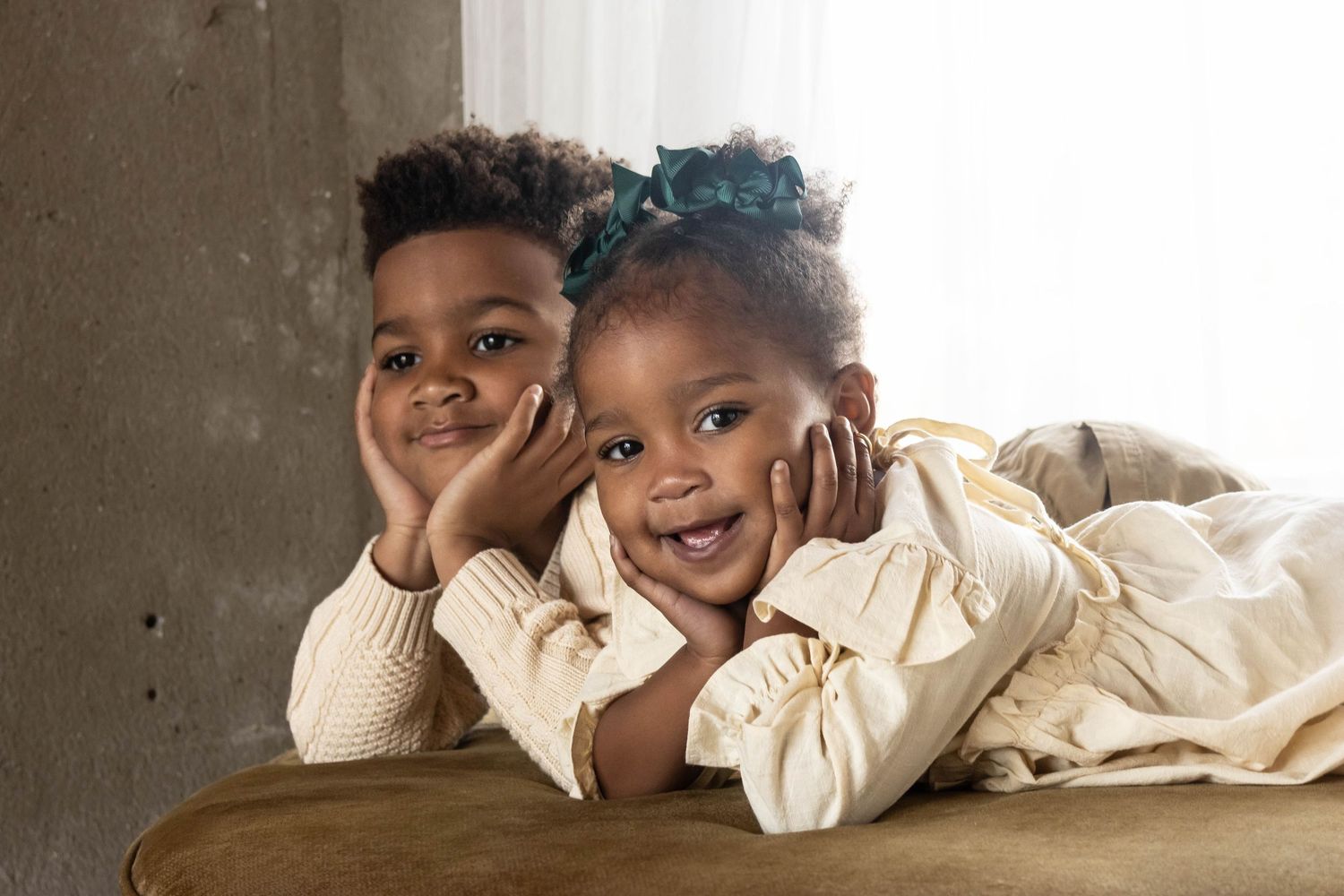 portrait of 2 african american kids laying with their hands under their chins.