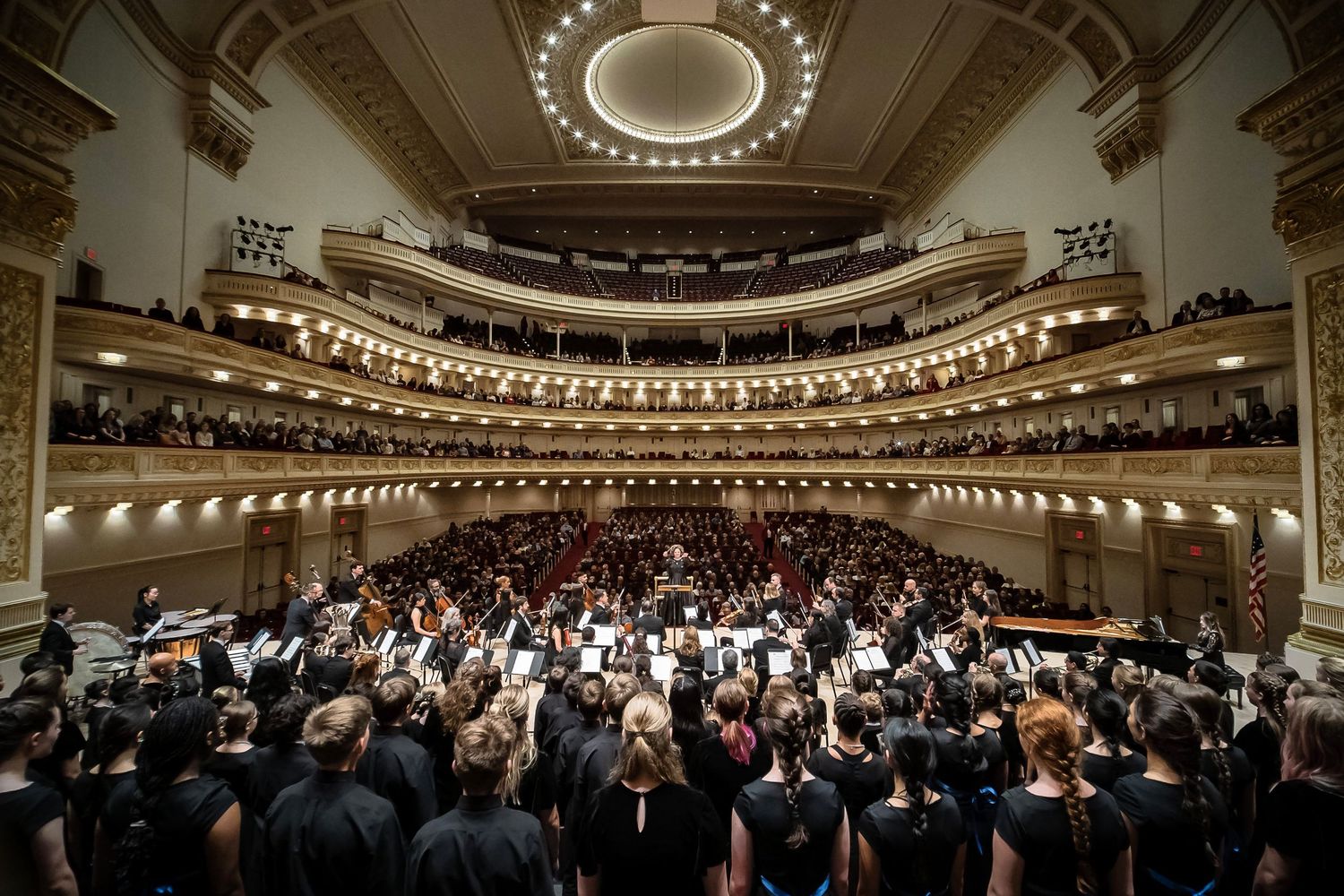 Full orchestra performing on stage at Carnegie Hall in NYC during a live classical concert