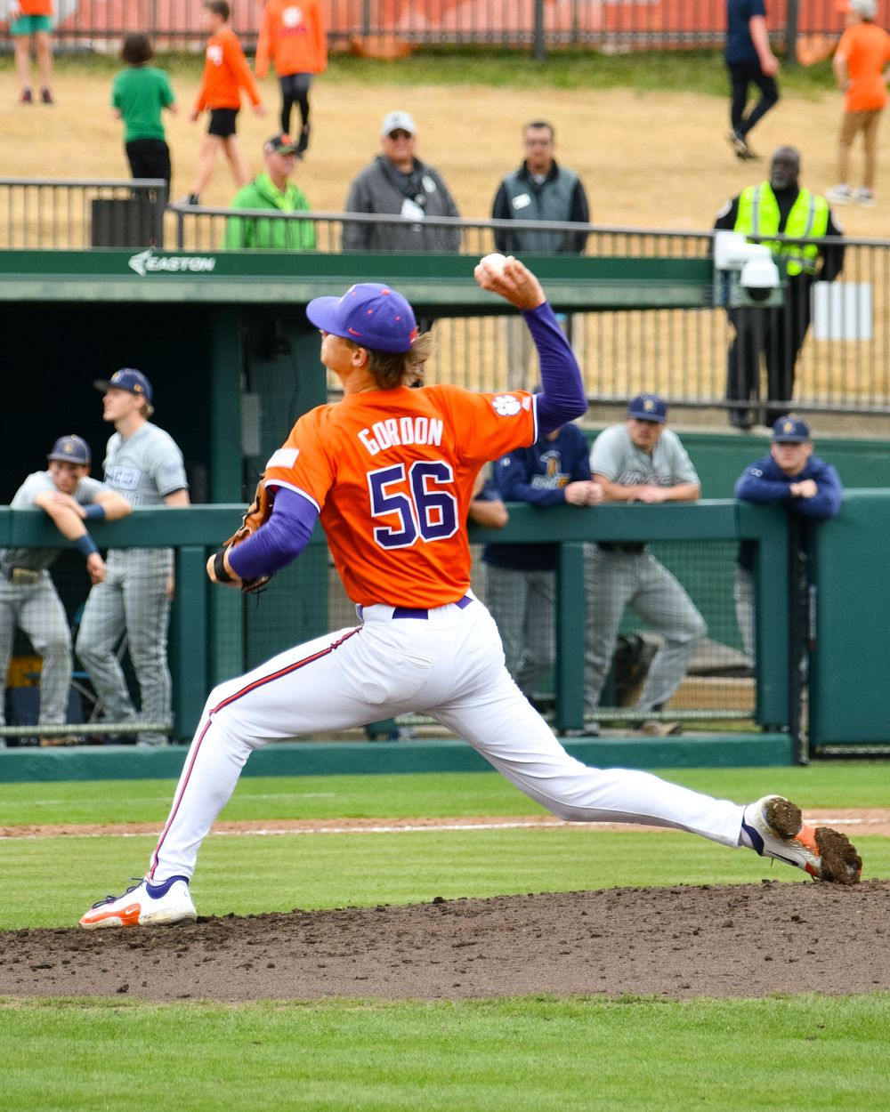 Baseball pitcher in orange Clemson uniform mid-throw on the mound during a game.