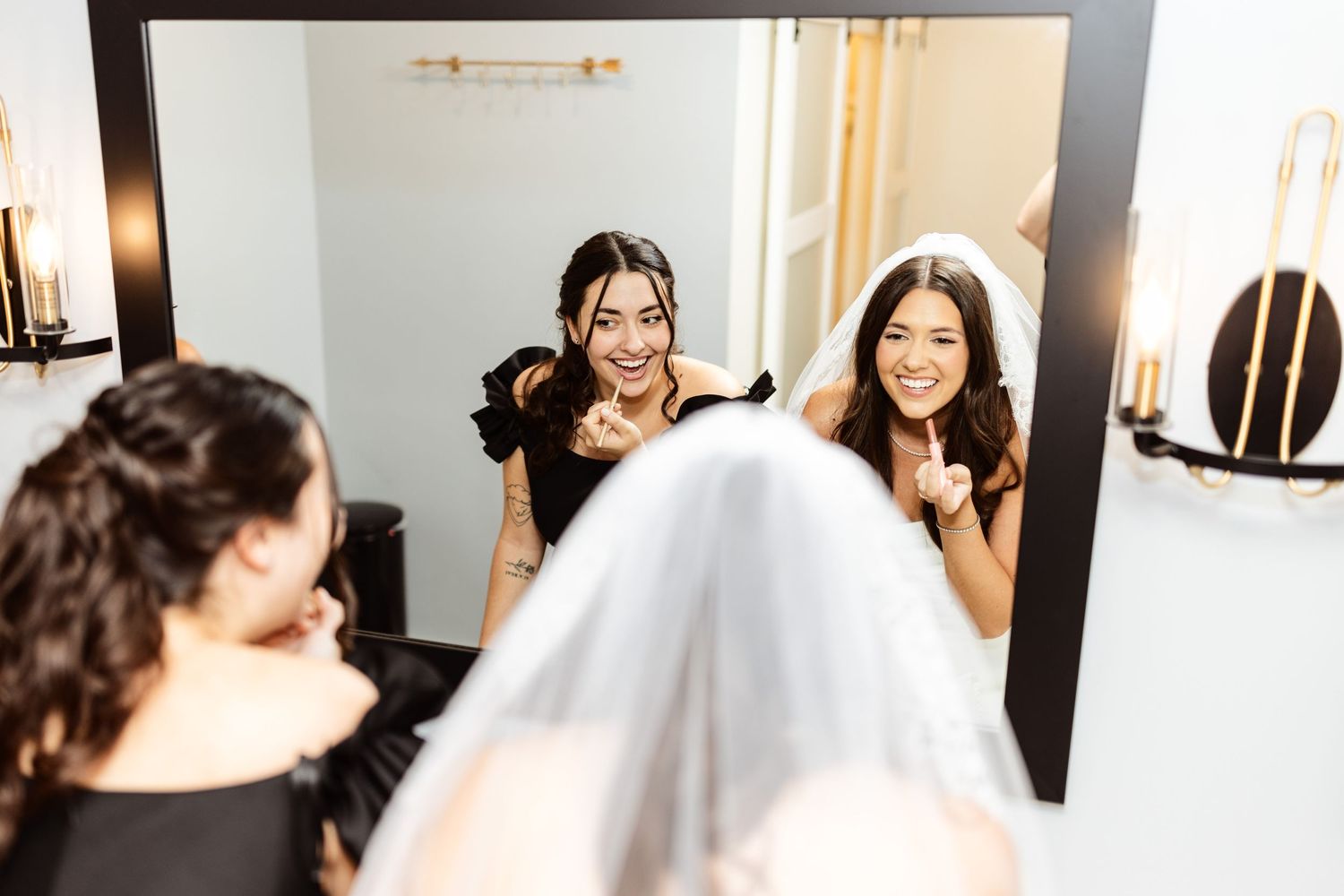 Wedding preparation scene showing reflections in mirror as bride gets ready with her party.