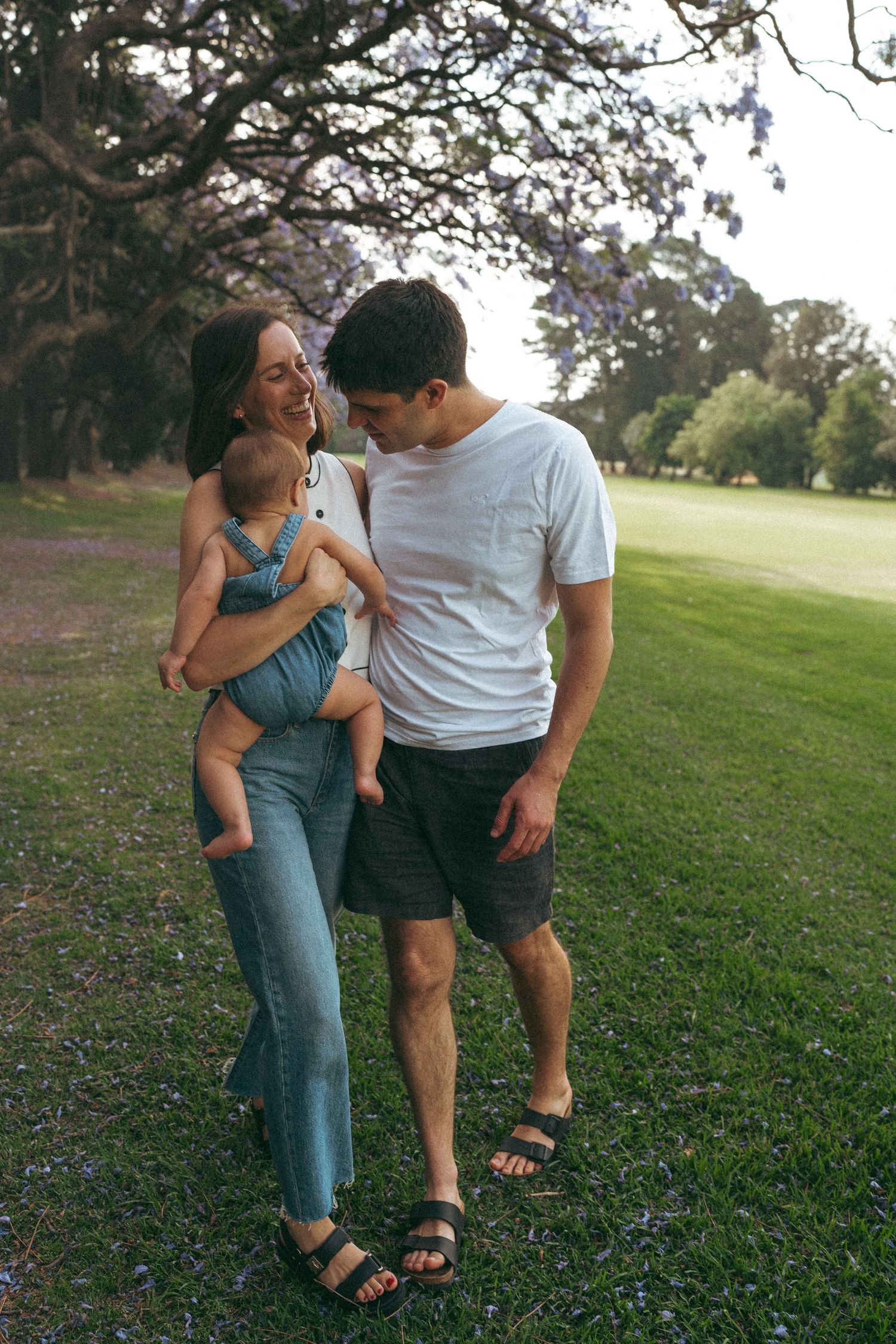 Family enjoying casual moments together outdoors on a grassy hillside.