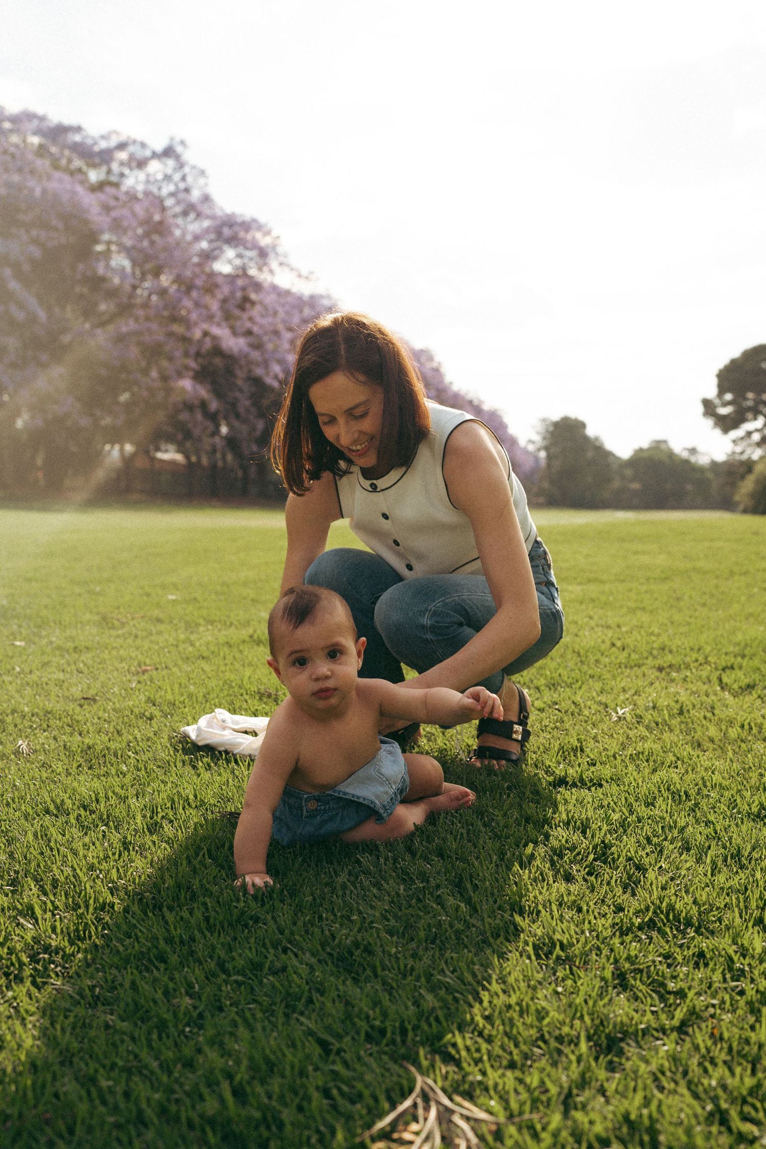 Family plays together on lush green grass under blooming cherry trees.