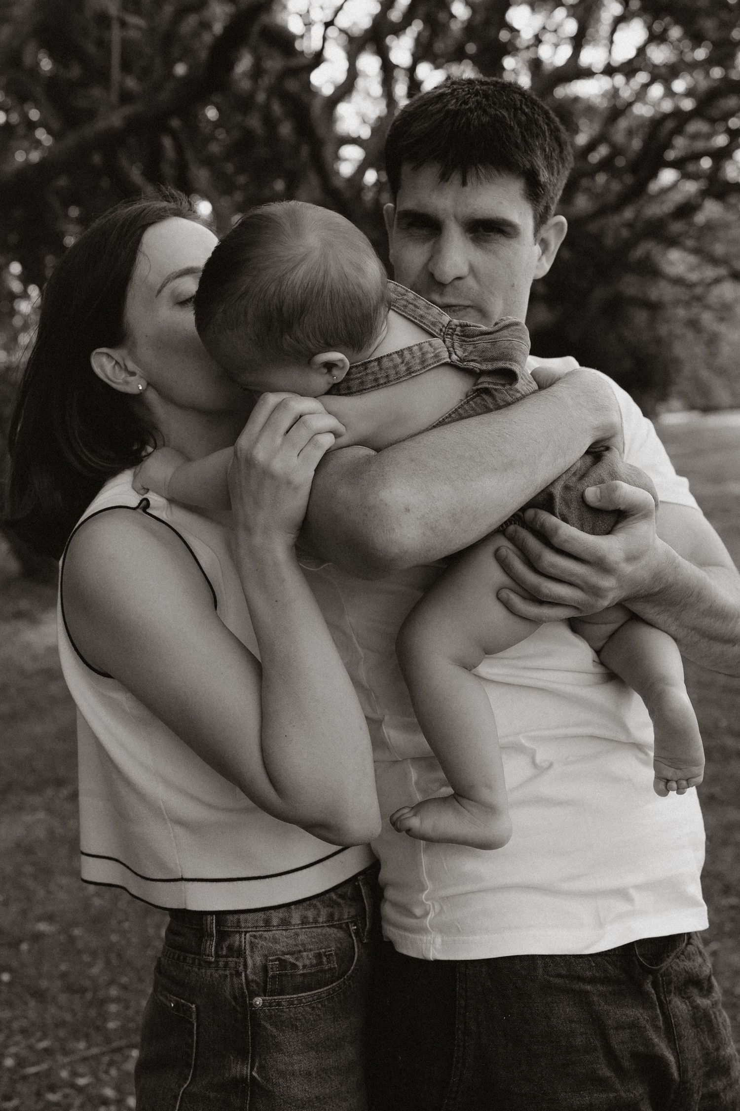 Black and white portrait of a family sharing an intimate moment outdoors.
