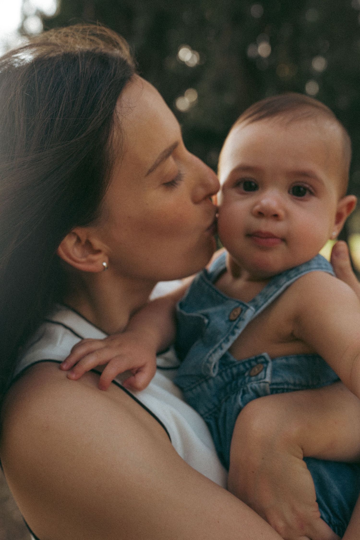 A gentle moment of connection between parent and infant in natural lighting.