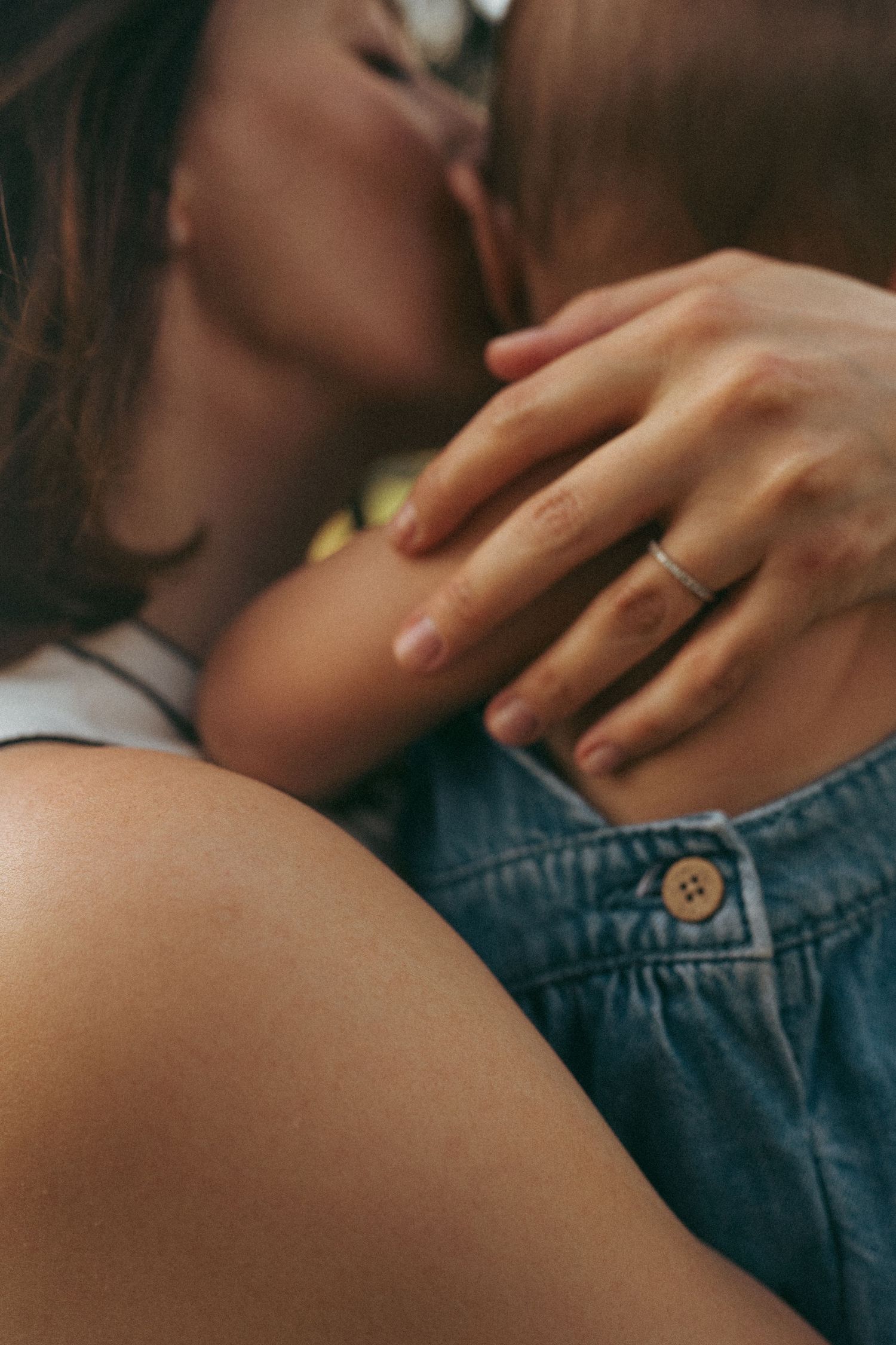 Close-up detail of hands and denim clothing during an intimate family moment.