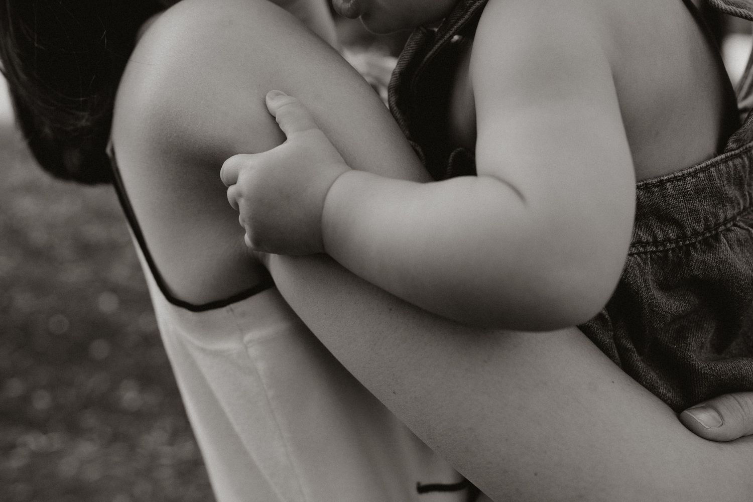 Black and white close-up of embracing arms in soft natural light.