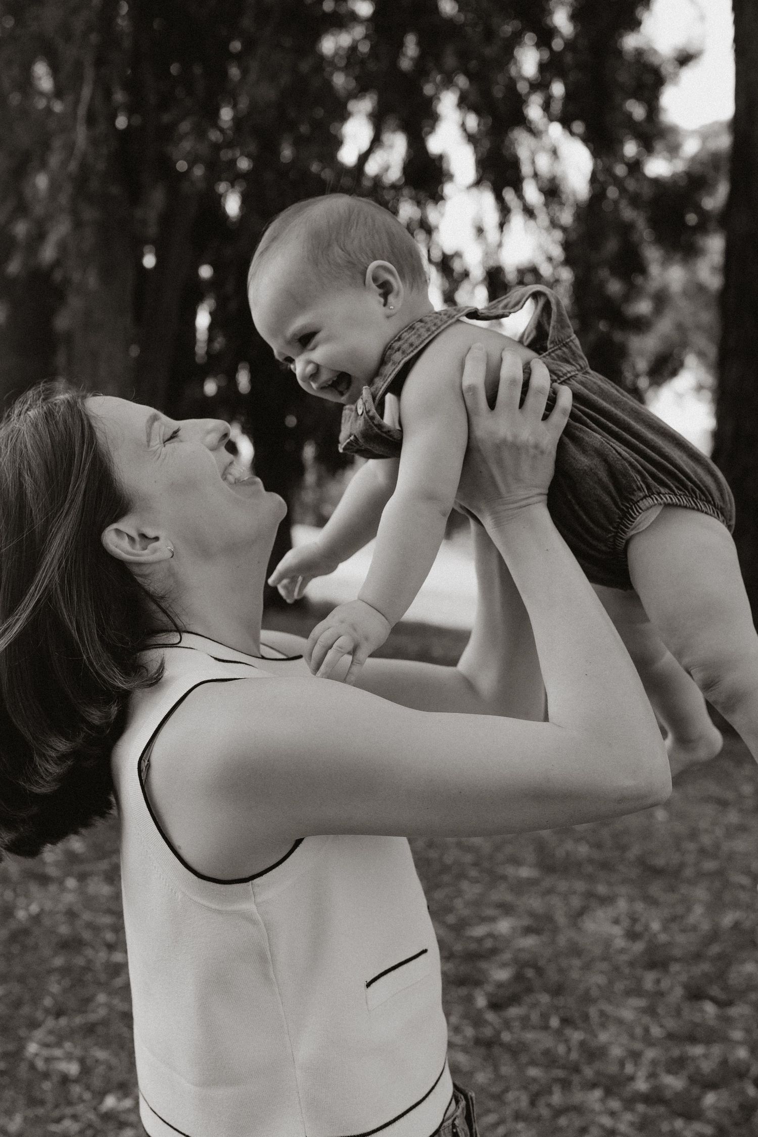 A joyful moment shared between parent and baby lifted in the air outdoors.