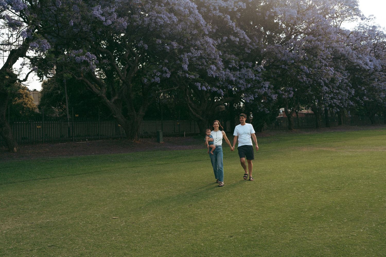 Couple enjoying a sunny day in a park with flowering trees in the background.