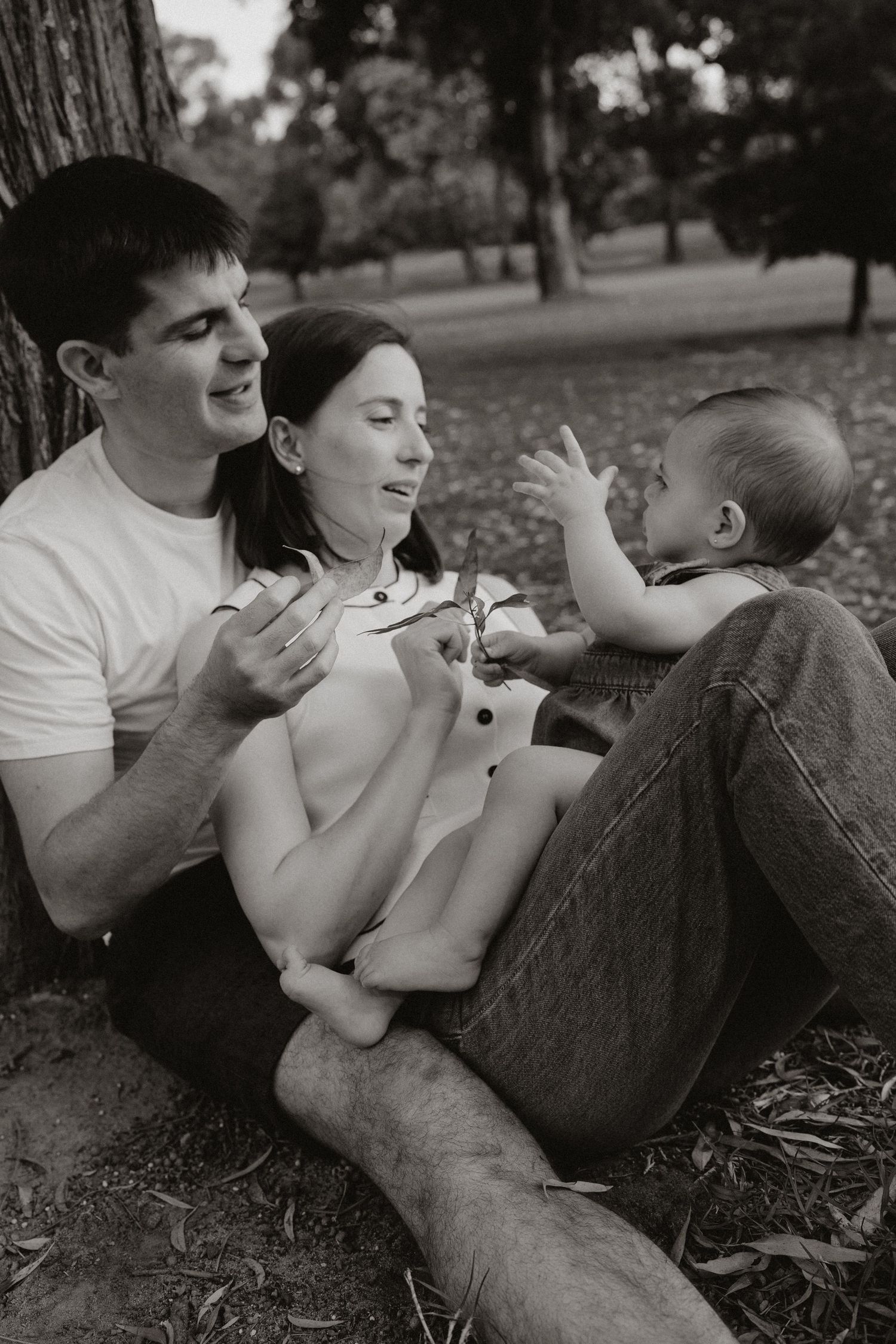 Black and white photo of family members relaxing together on fallen leaves.