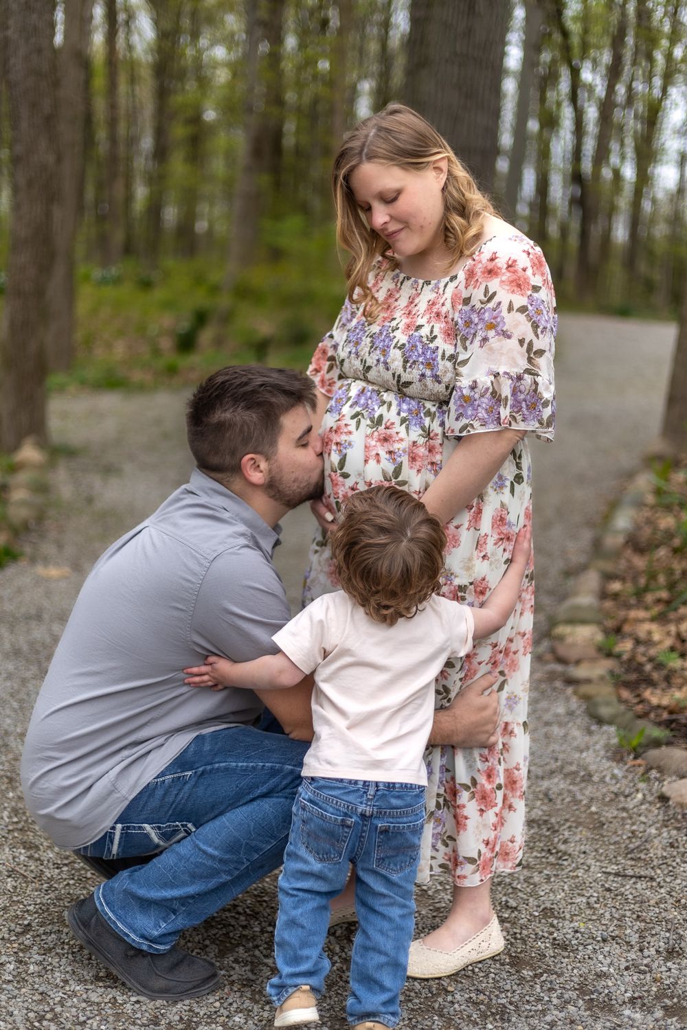 A touching family maternity moment shared on a woodland path in springtime.