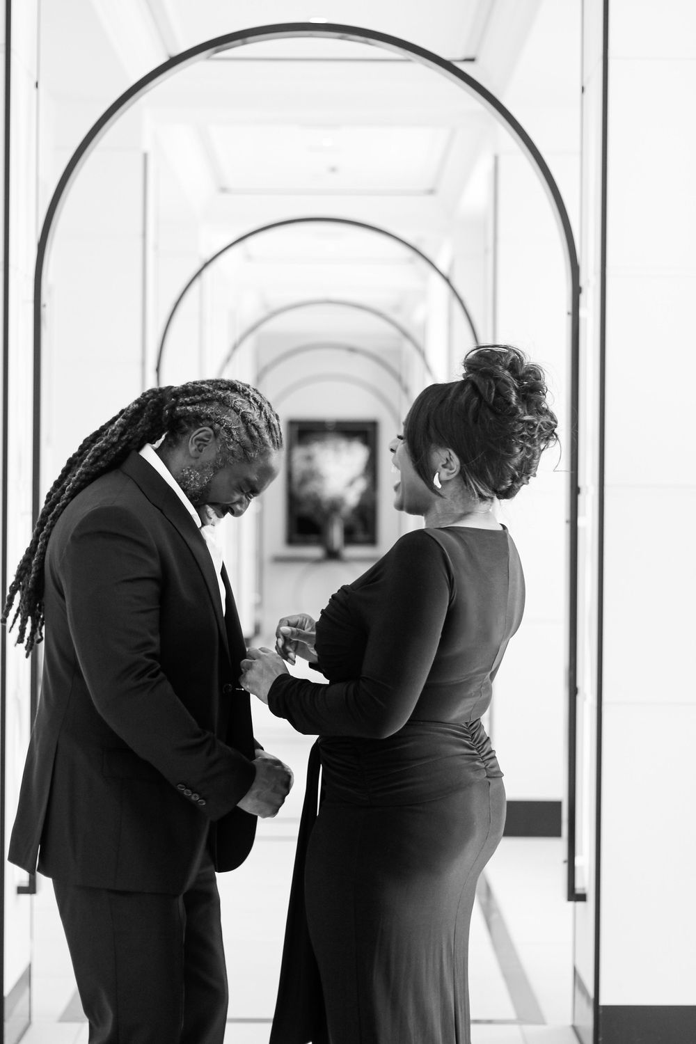 Intimate silhouette portraits in formal wear against bright white arched hallway.