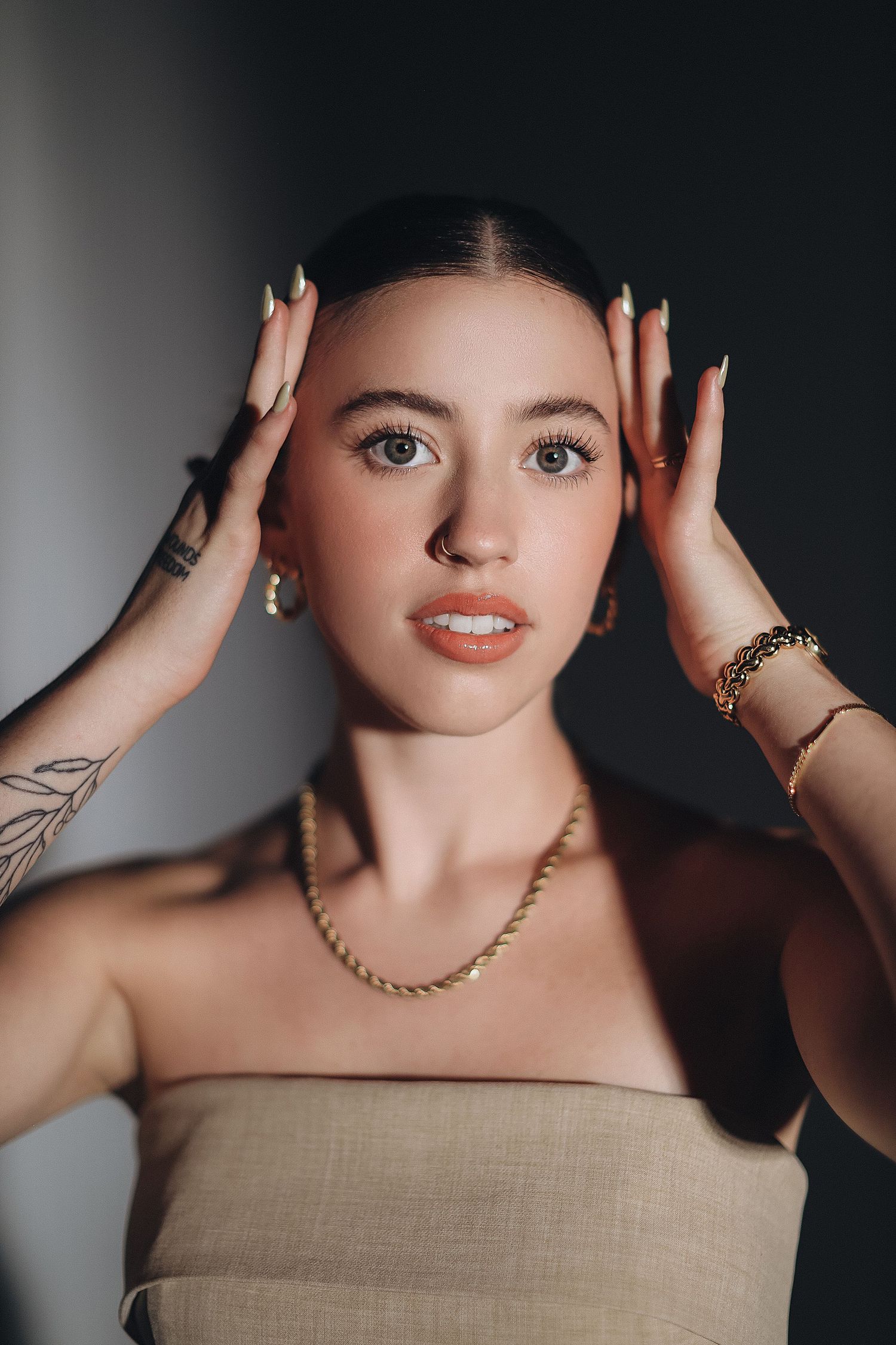 Close-up beauty portrait of woman wearing gold jewelry and neutral makeup.