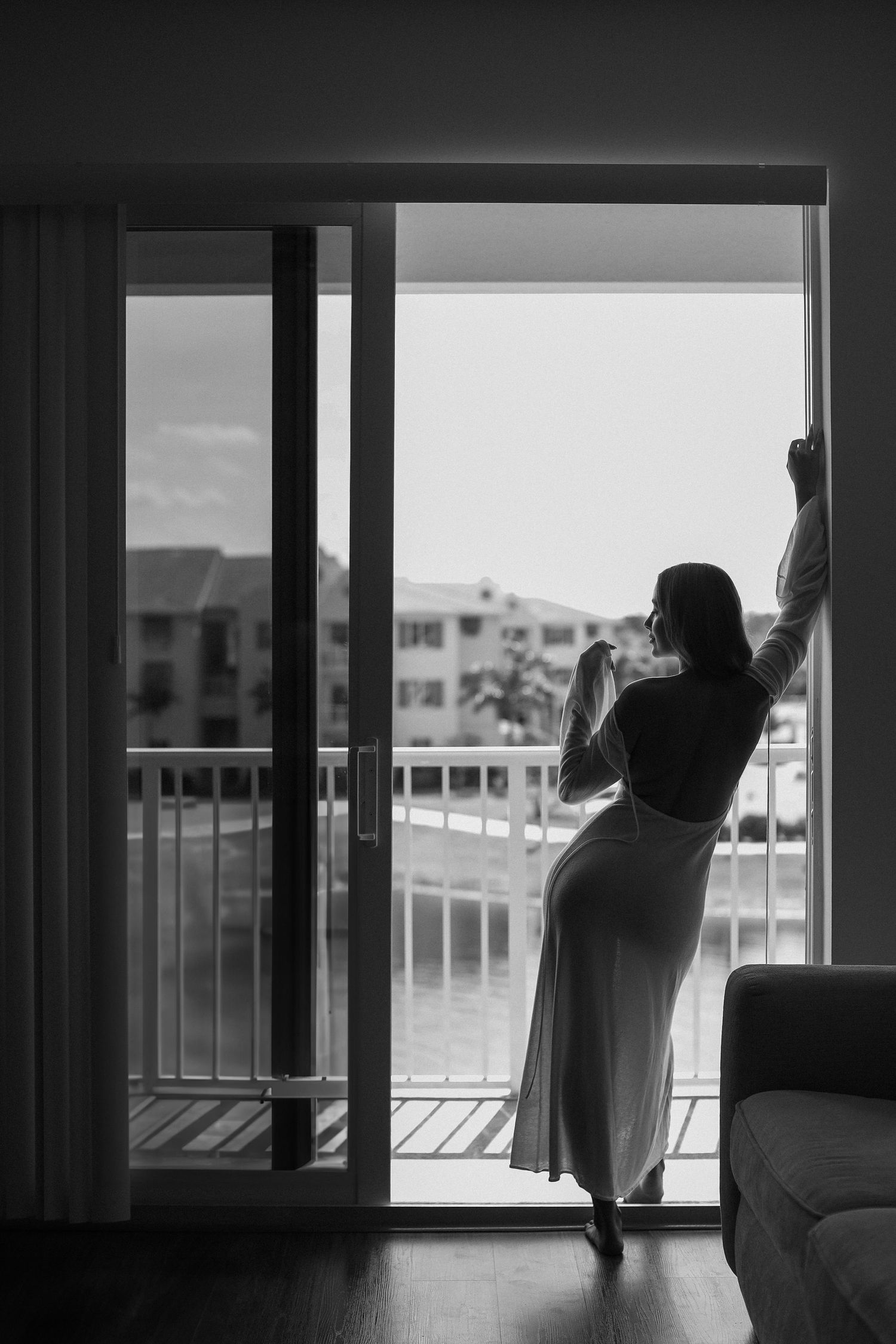 Silhouette of a person stretching by glass doors on a balcony in black and white.