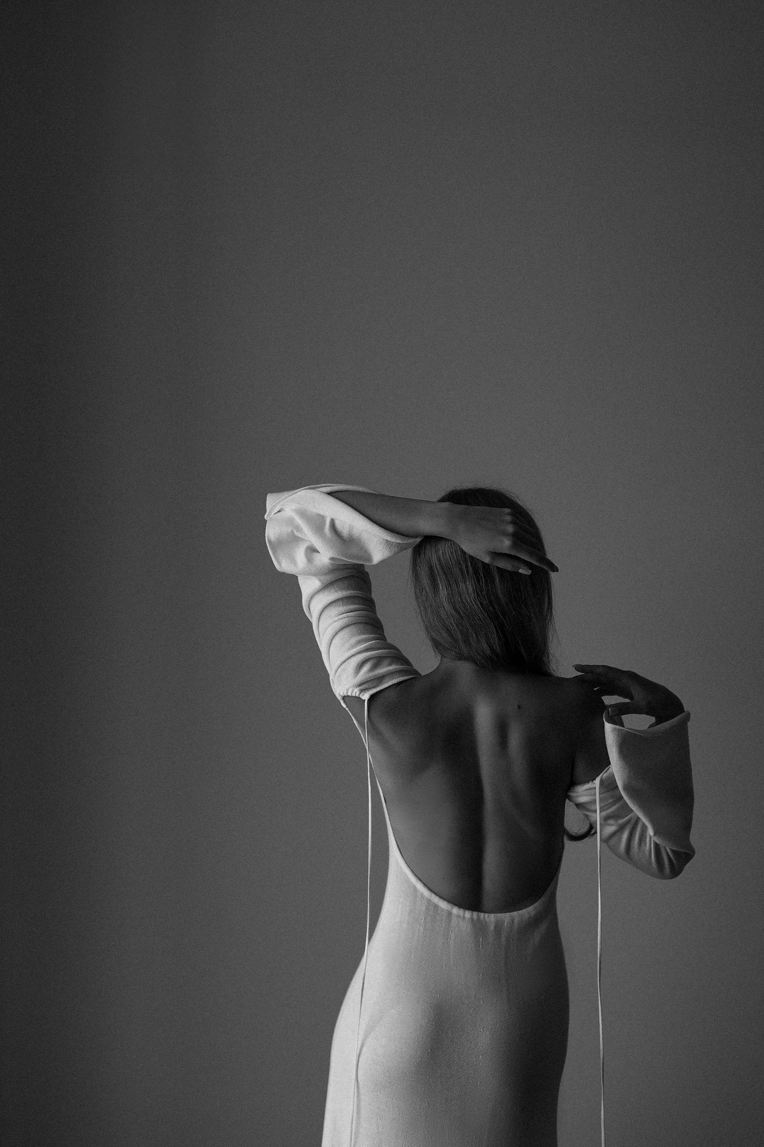 Artistic black and white photo showing the back view of someone in a backless dress.