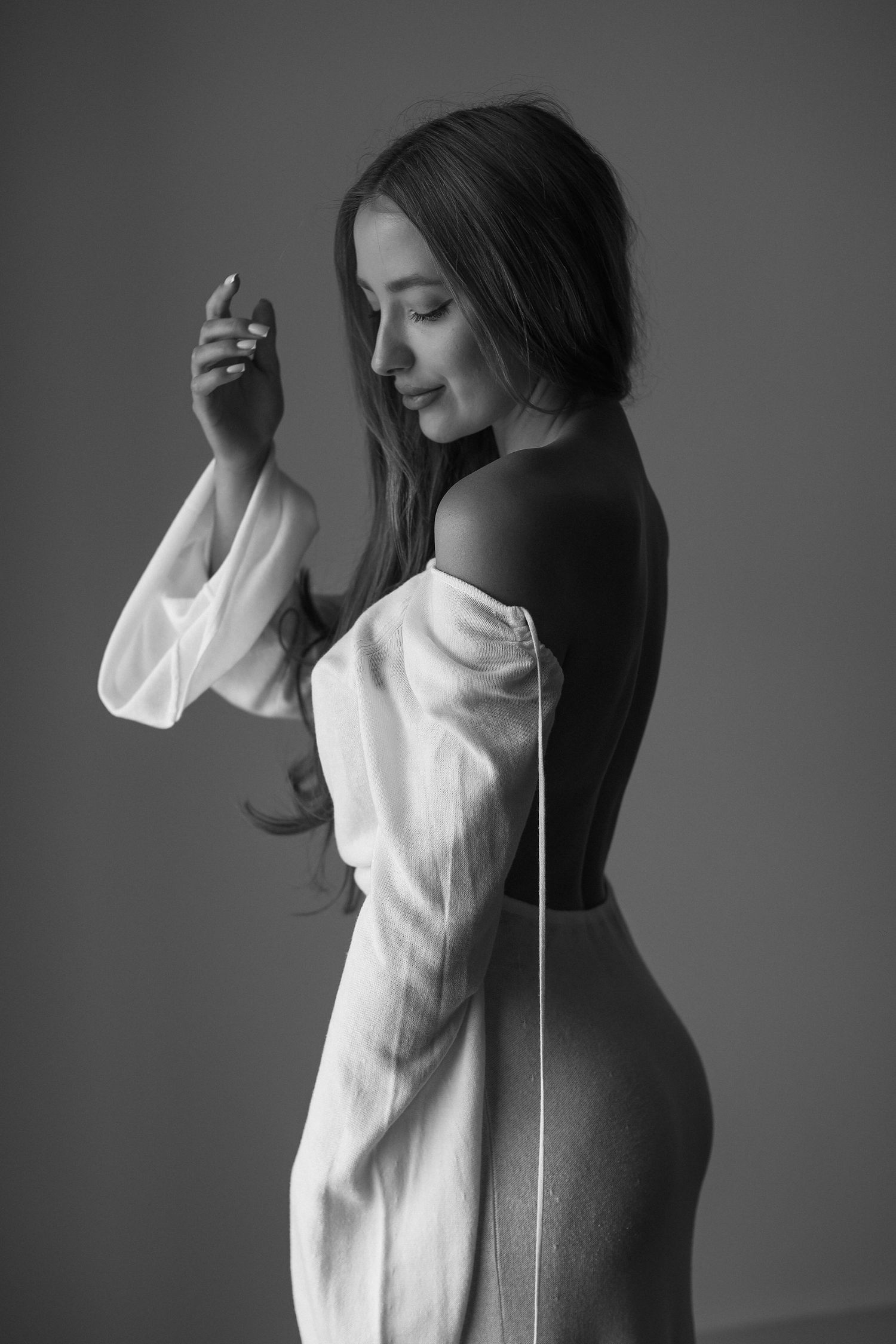 Black and white artistic portrait of a person in an elegant white off-shoulder dress.