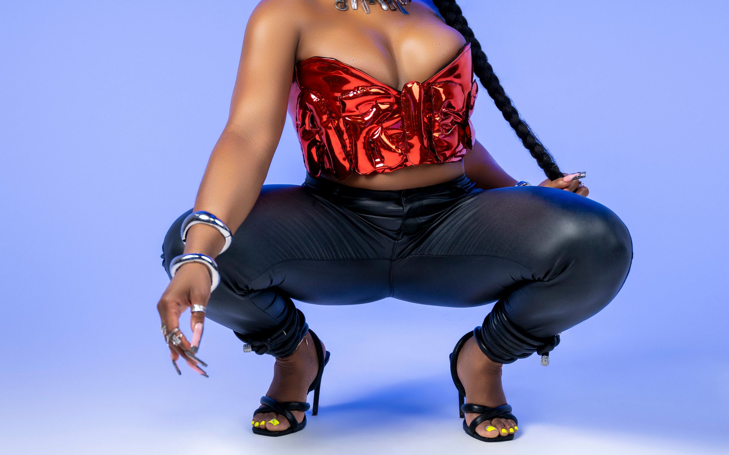 Dancer in red metallic top and black pants crouches in dynamic pose.