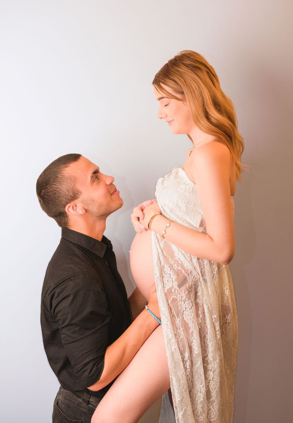 Tender maternity moment captured with couple in white dress and black shirt.