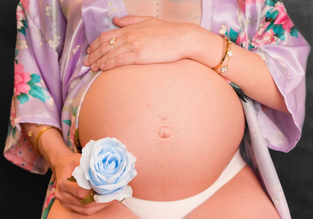 Delicate maternity photos with blue rose accent and floral robe details.