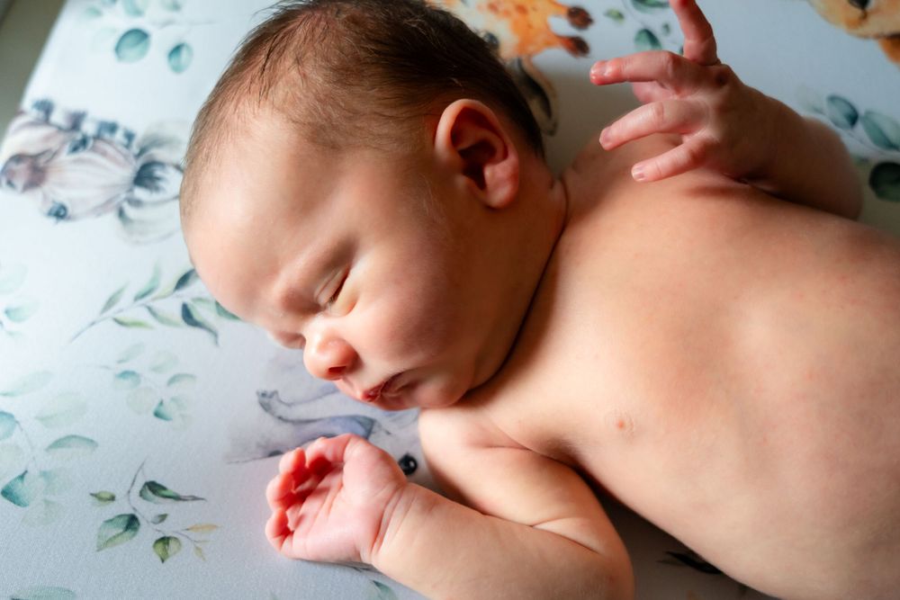 Sleeping newborn on floral patterned fabric in natural lighting.