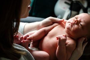 Newborn baby stretching during a relaxed moment with caregiver.