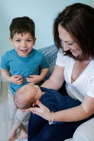 Family shares joyful moment together on light colored couch.