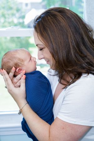 Tender moment shared between parent and infant near bright window.