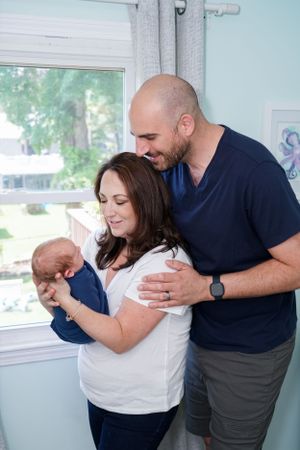 Family shares intimate moment together near window with natural light.