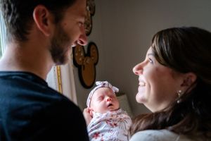An intimate family moment with baby nestled between parents in a dimly lit room.