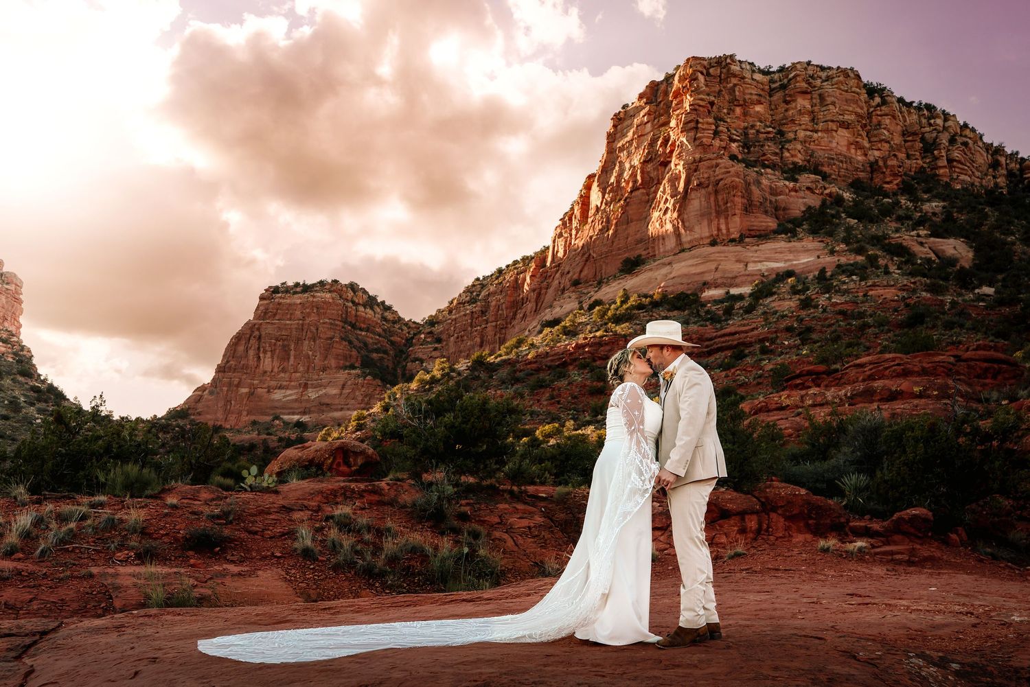 Couple kissing during elopement among red rock formations in Sedona, Arizona at sunset.