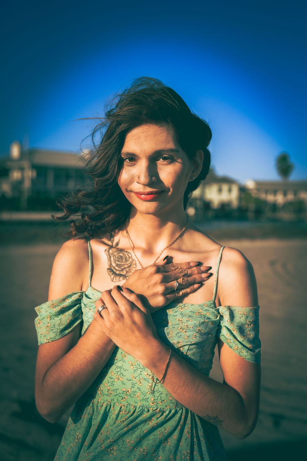 A dreamy portrait in mint green dress with golden sunlight showcasing intricate henna designs on hands against a blue sky.