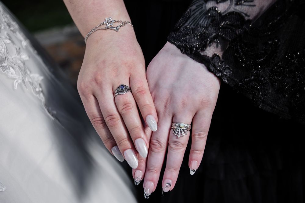 Close-up detail shot of hands showing wedding rings and tattoos.