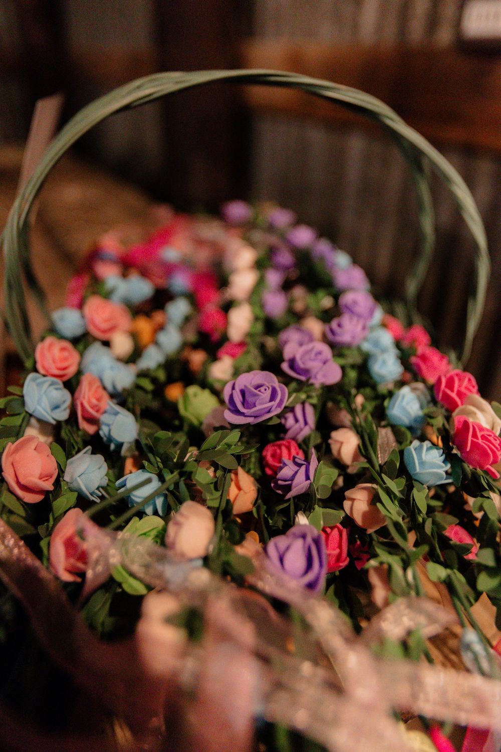 A colorful basket arrangement of pink, purple, and blue roses with greenery.
