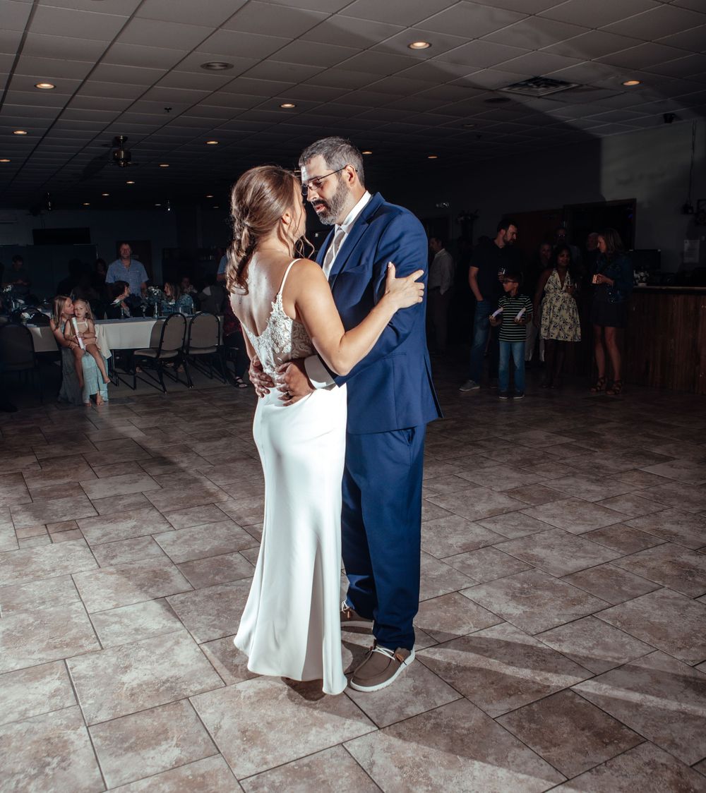Couple dancing together on tiled floor at wedding reception.