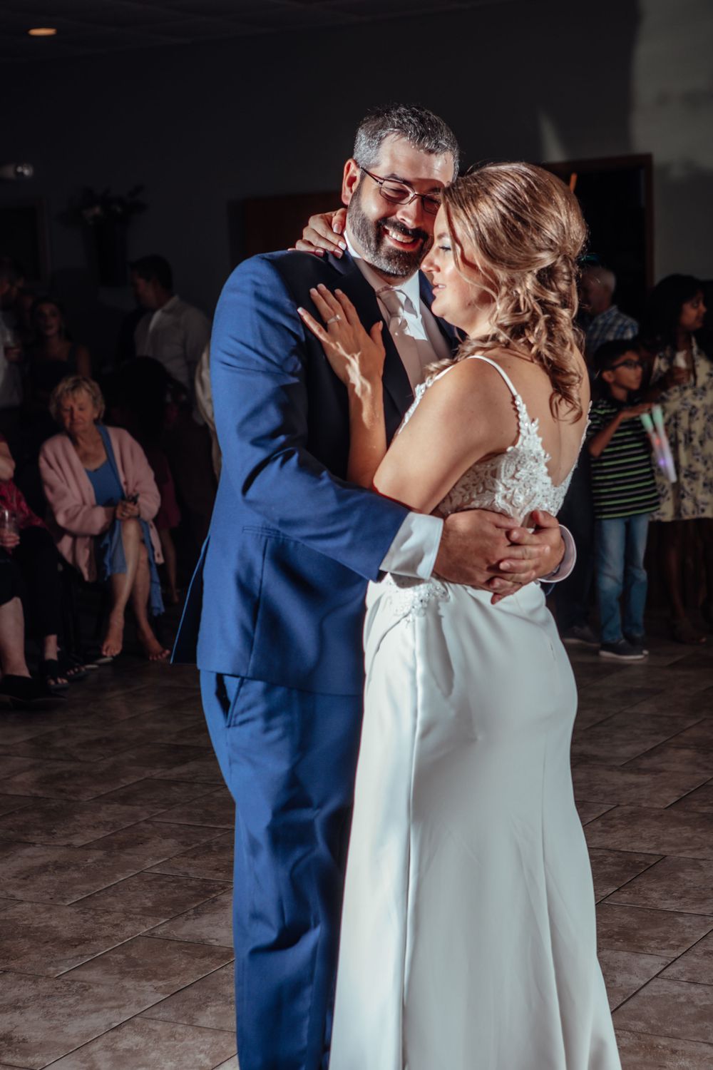 Wedding couple sharing first dance in dimly lit reception venue.