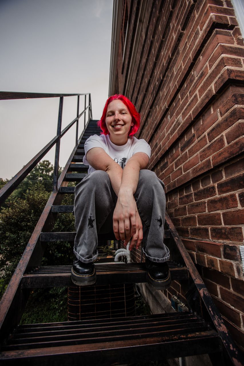 Creative portrait session on brick building fire escape with urban industrial feel.