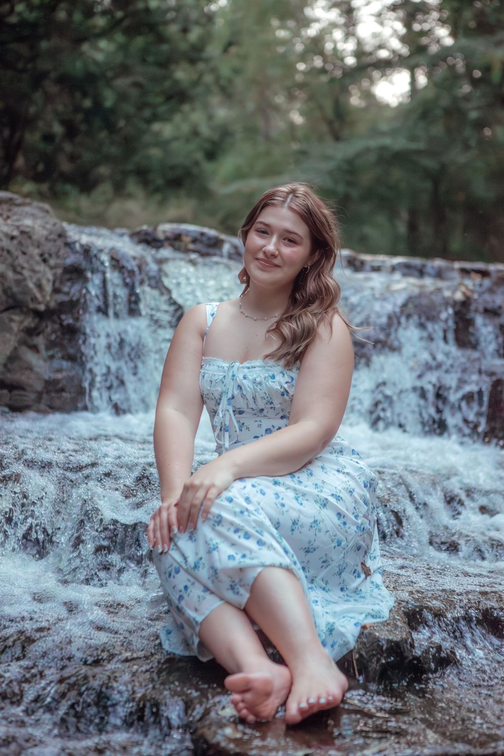 Dreamy photoshoot at a waterfall with someone in a light blue floral dress.
