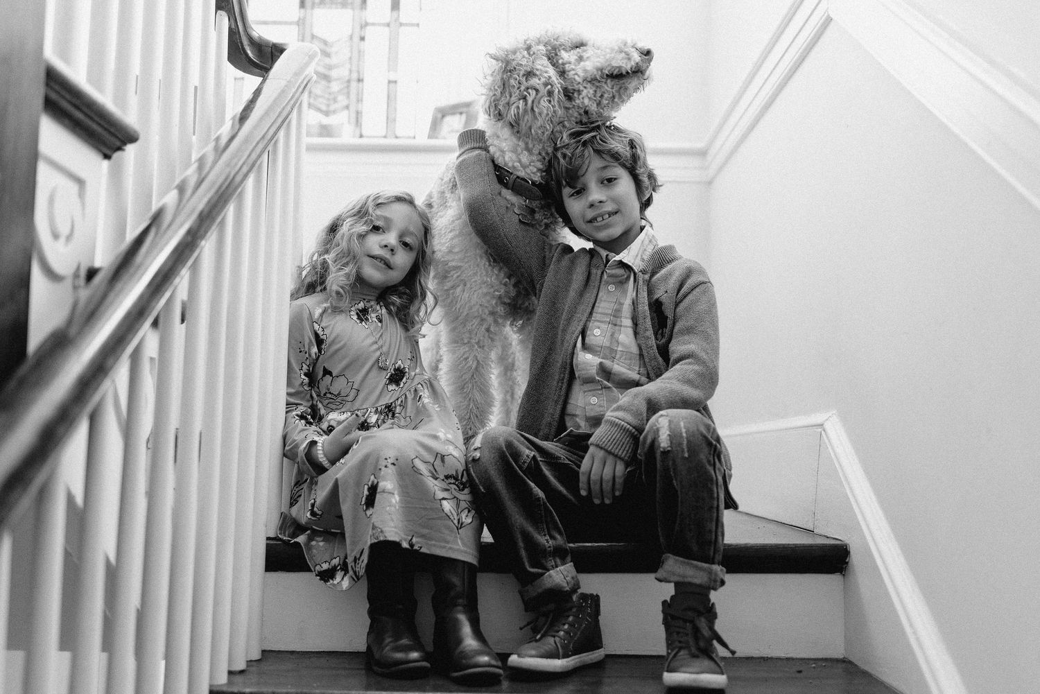 Black and white view through doorway showing a family reading together on a couch with a dog resting on the floor.