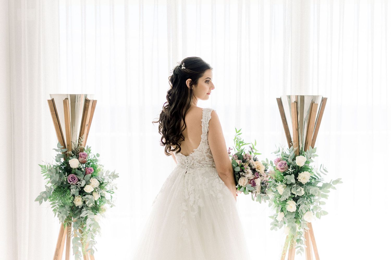 Back view of bride in lace wedding dress with floral arrangements.