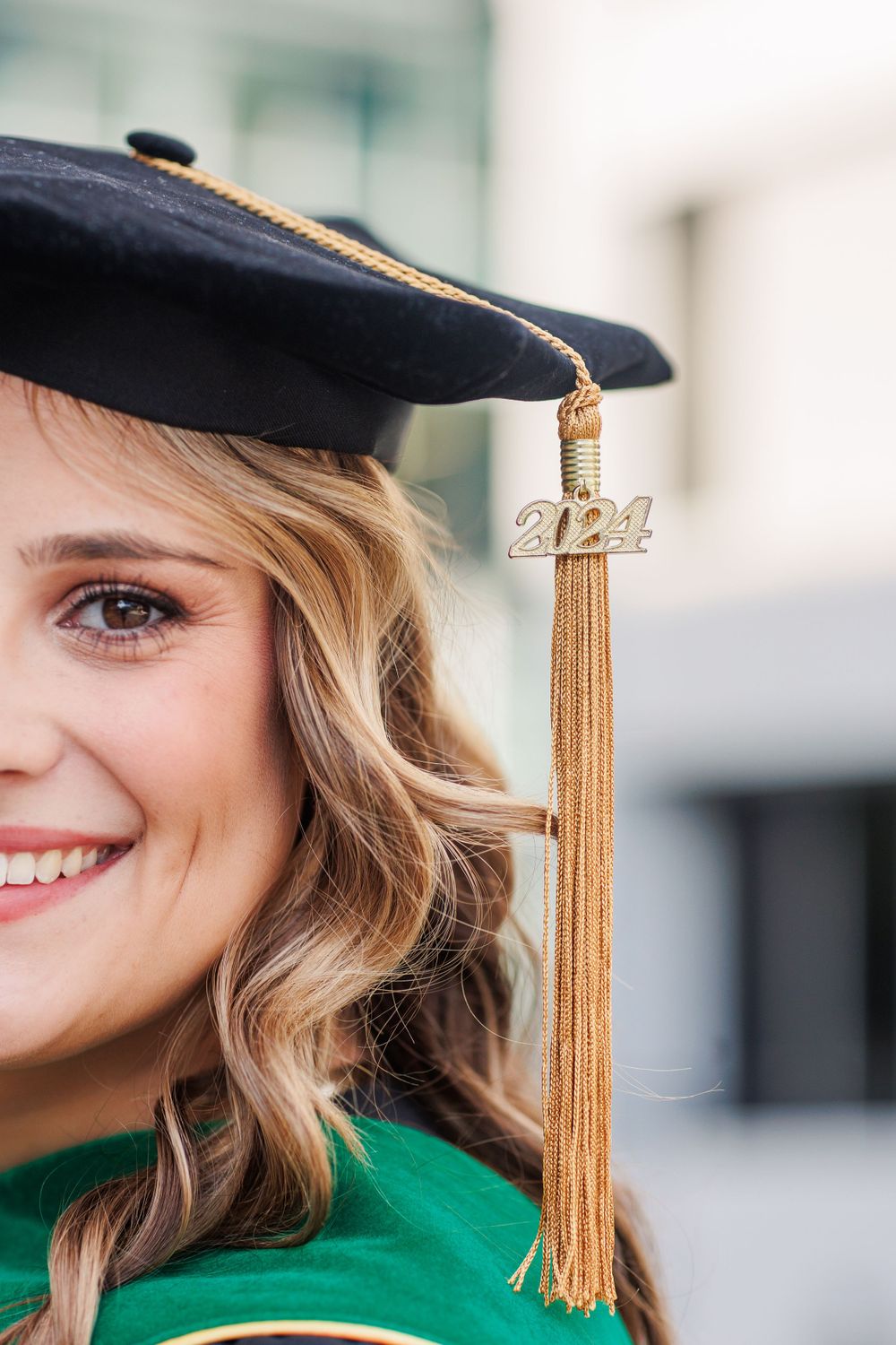A graduation portrait showing a gold tassel and graduation cap against a blurred background.