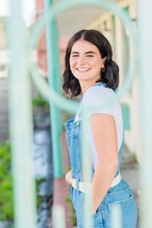 Person in casual outfit poses against turquoise pillars outdoors.